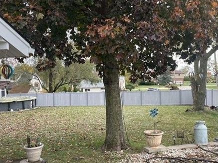 A backyard with a white fence and a tree