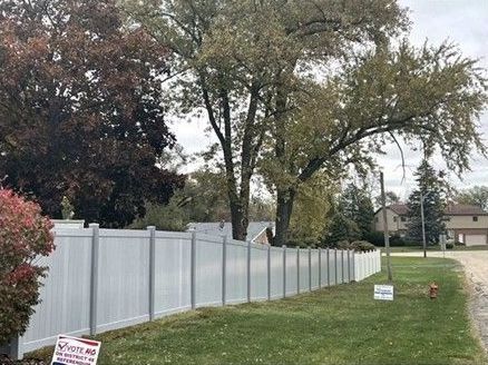 A white vinyl fence surrounds a lush green yard.