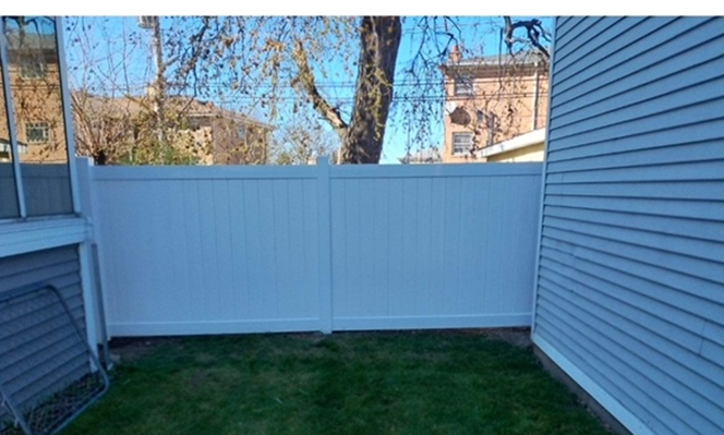 There is a white fence in the backyard of a house.