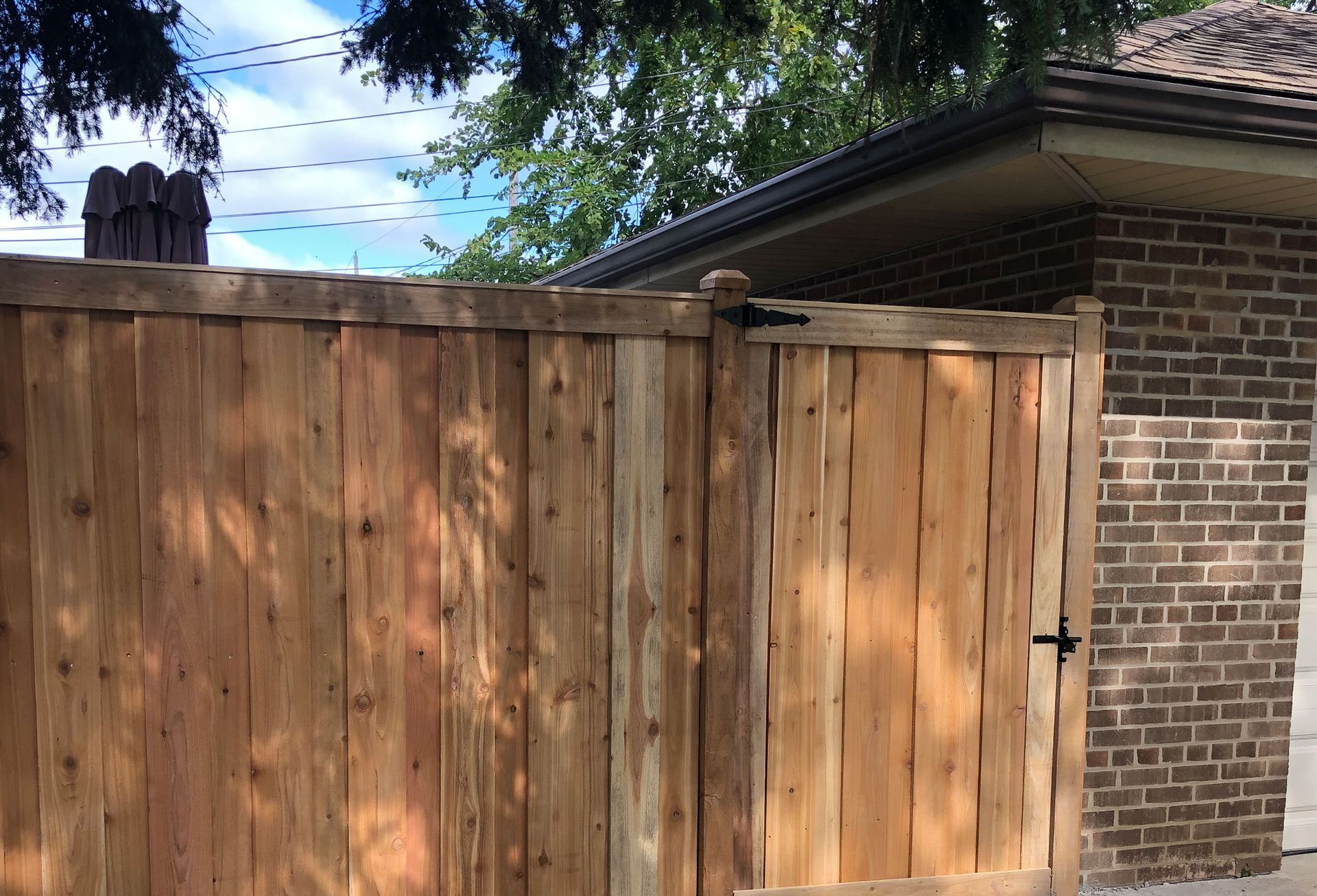 A wooden fence with a gate in front of a brick building.