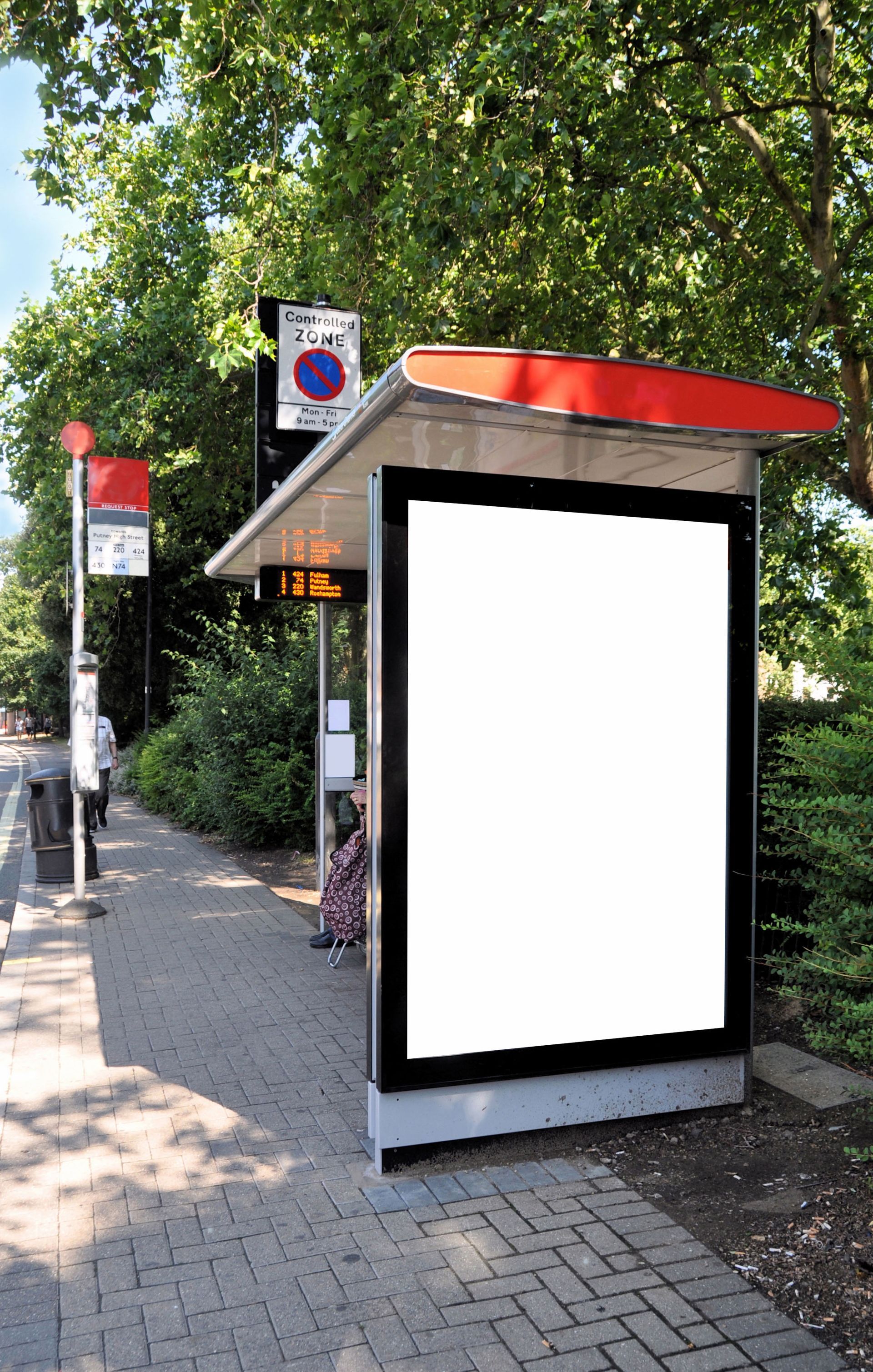 Bus stop shelter with a blank advertising display. Red and black accents, trees in the background.