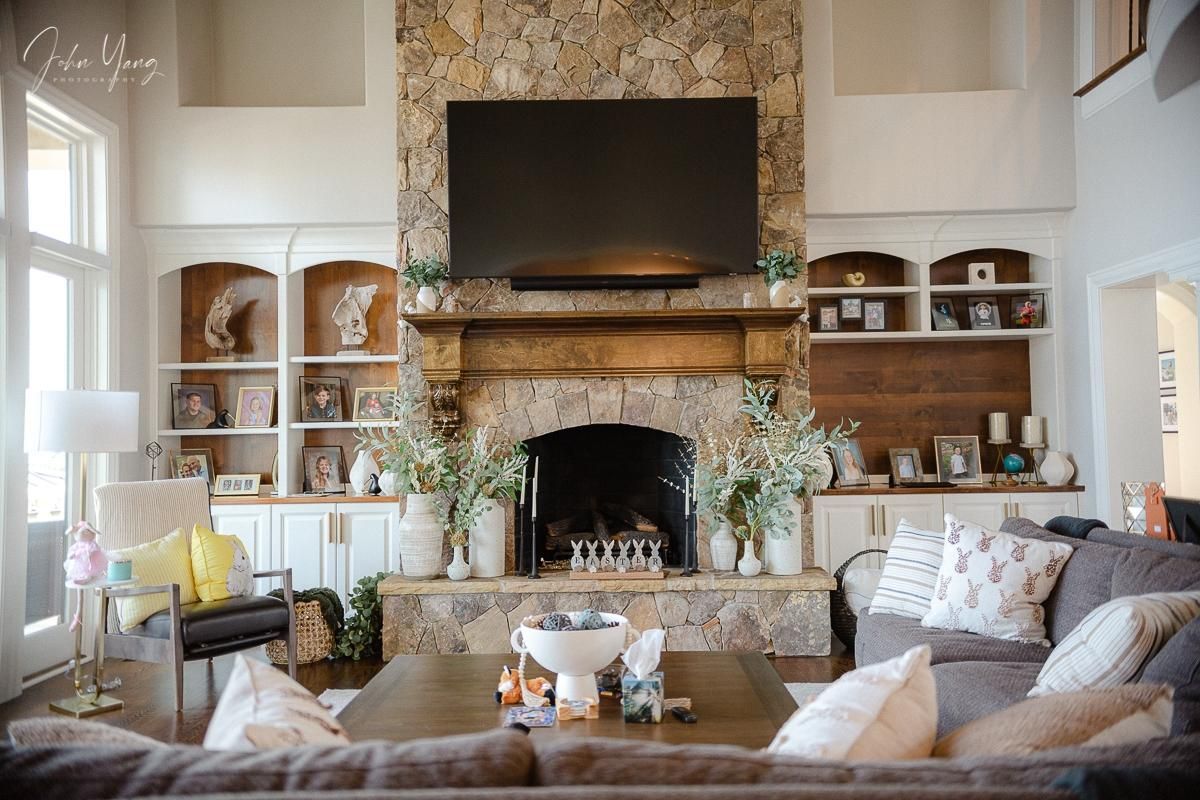 Living room with stone fireplace, TV, built-in shelves, sofa, and coffee table.