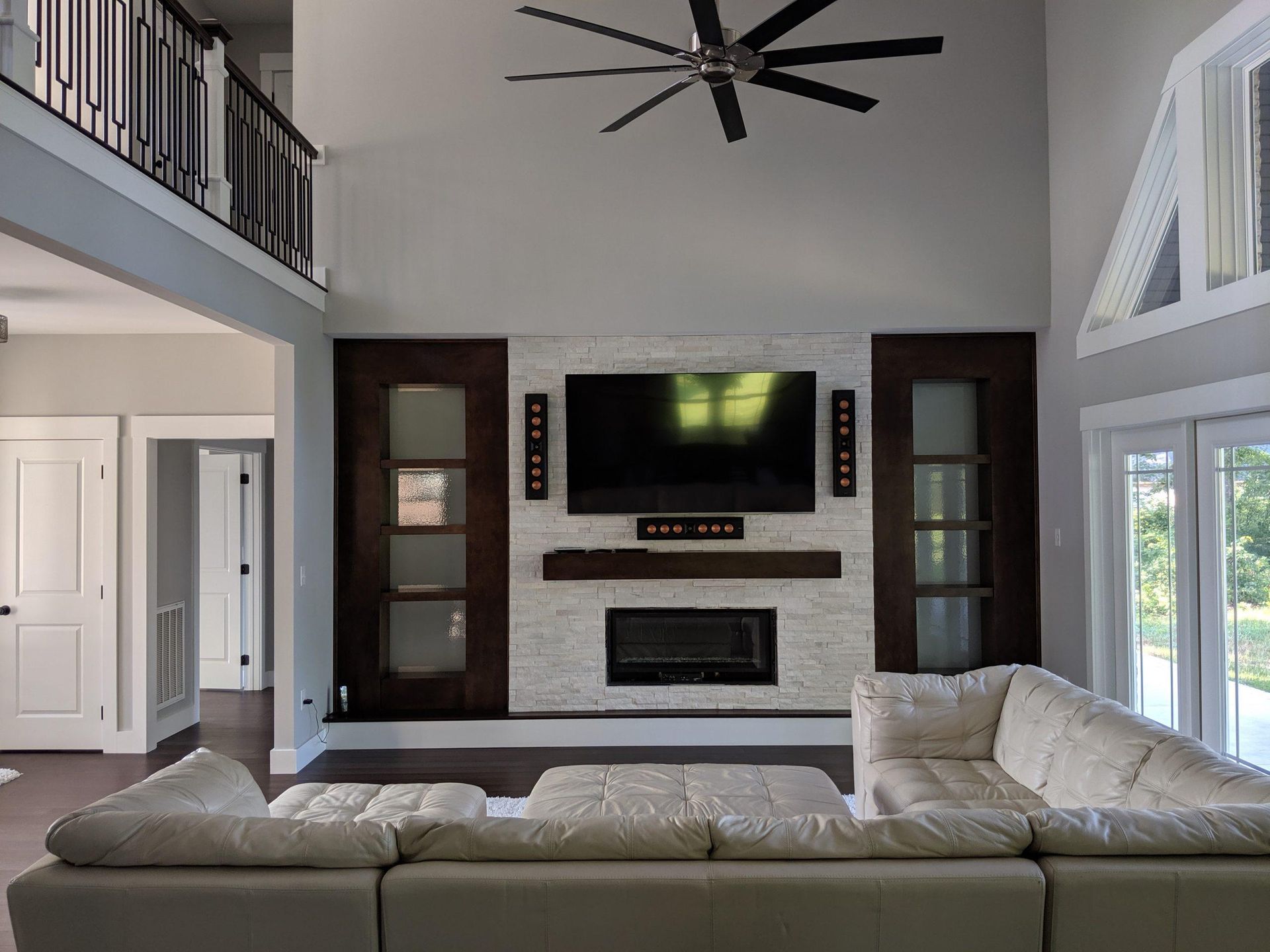 Living room with vaulted ceiling, TV, fireplace, sectional sofa, and a balcony.