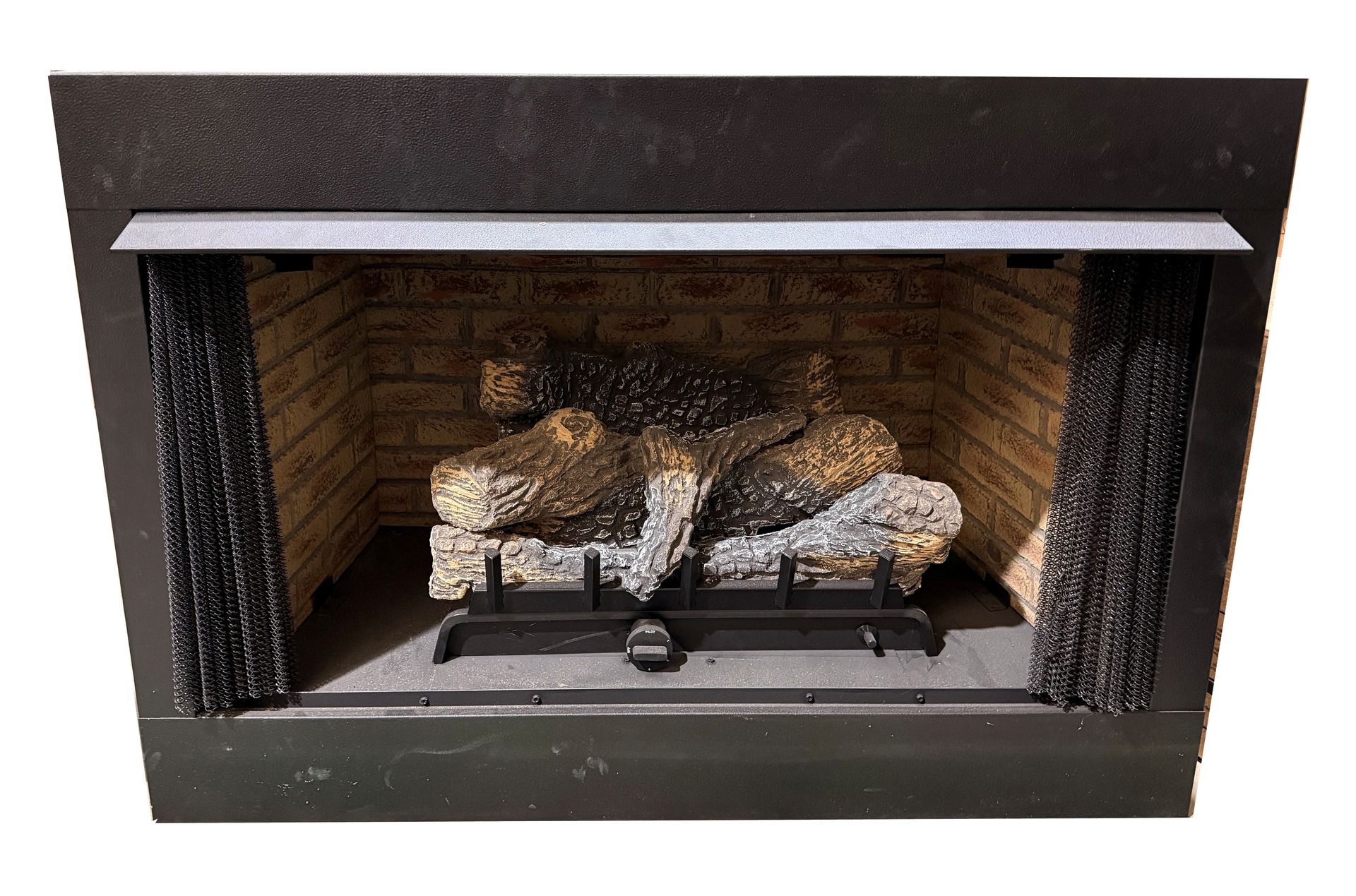 Decorative gas fireplace with log set inside a black metal and brick-lined surround