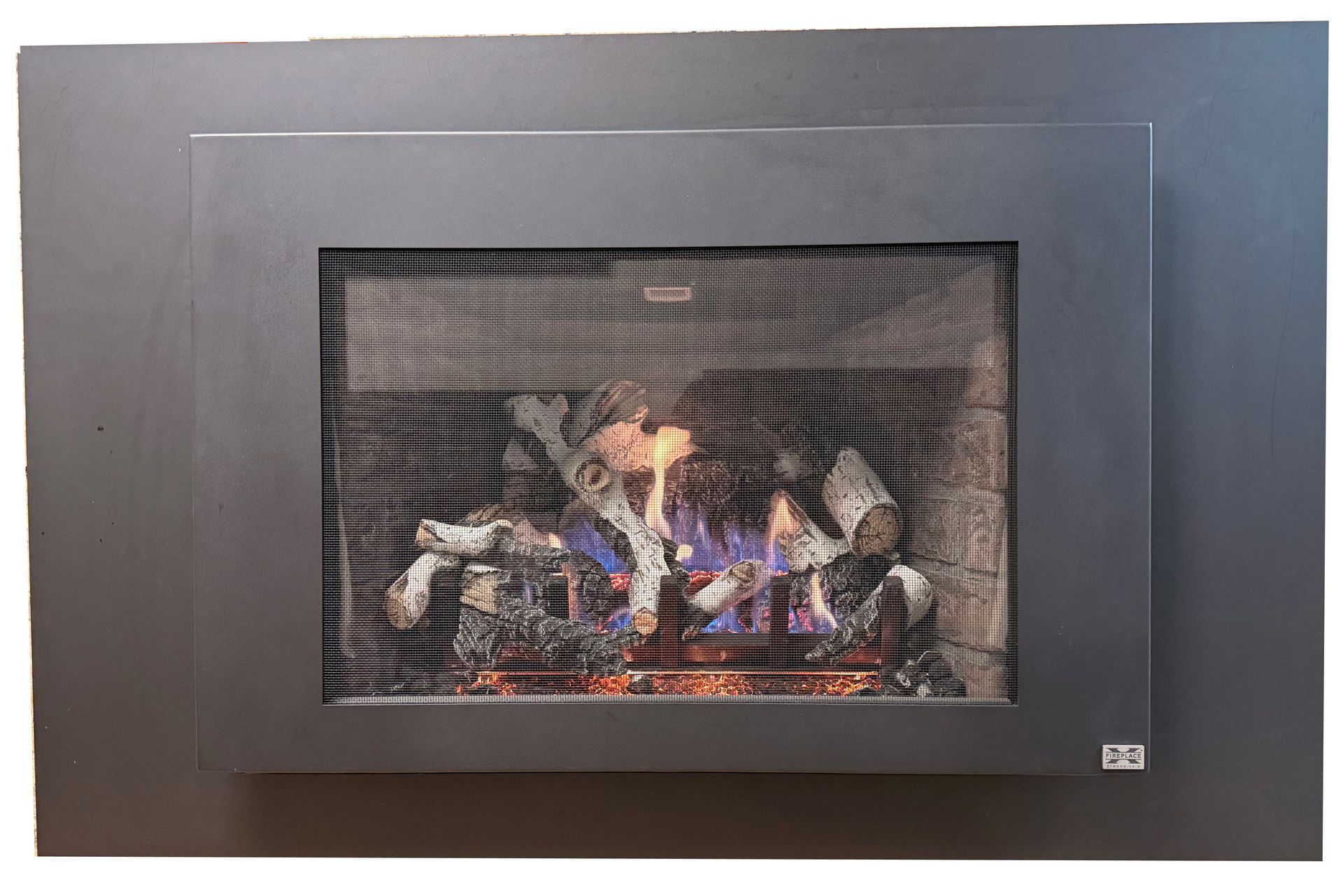 A modern, rectangular gas fireplace with a dark metal surround and a visible flame burning over decorative logs.