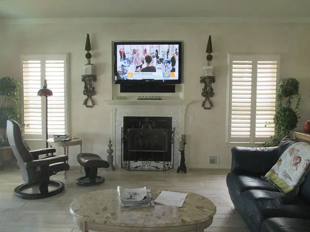Living room with fireplace, TV, and furniture, featuring a black leather sofa and a recliner.
