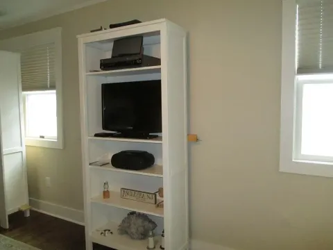White bookshelf with TV, media components, and decorative items against a beige wall.