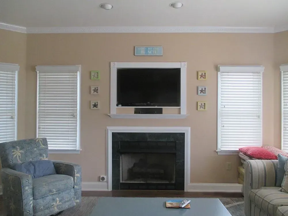 Living room with fireplace, TV, windows with blinds, and blue-toned furniture.
