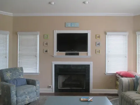 Living room with fireplace, TV, windows with blinds, and blue-toned furniture.