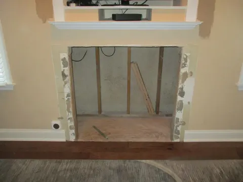 Fireplace under construction with wood and cream-colored walls.