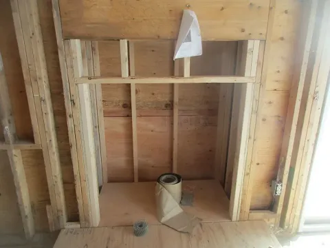 Wooden fireplace frame under construction, with lumber and paper.