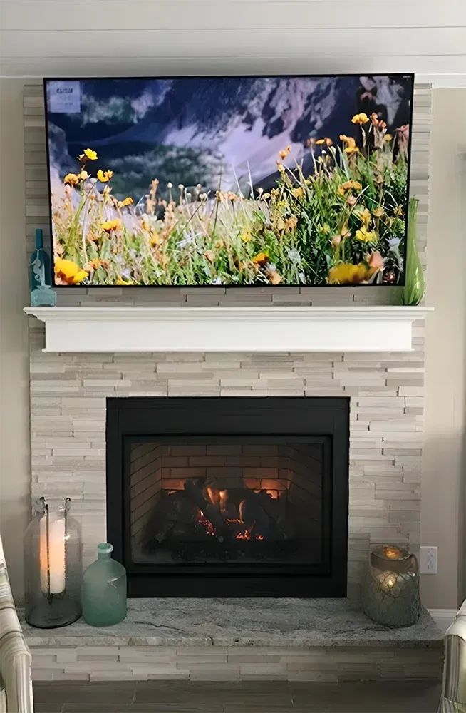 Fireplace with a lit fire, TV above, and decorative items.
