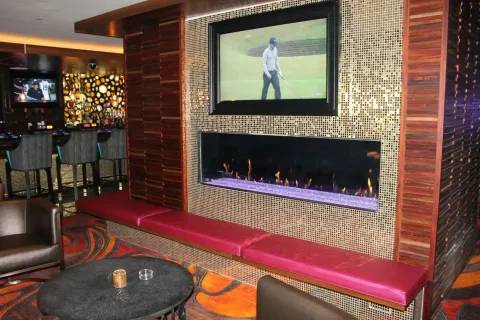 Cozy bar area with TV, fireplace, red bench, and a round table.