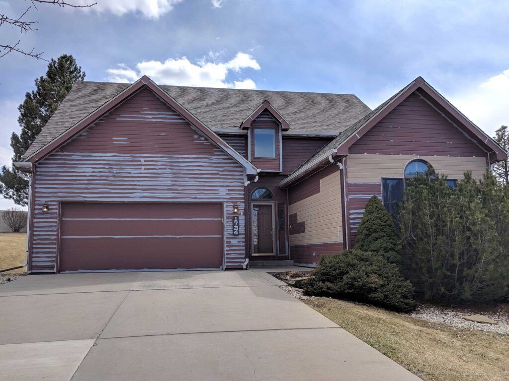 House with peeling red siding and a gray garage door.