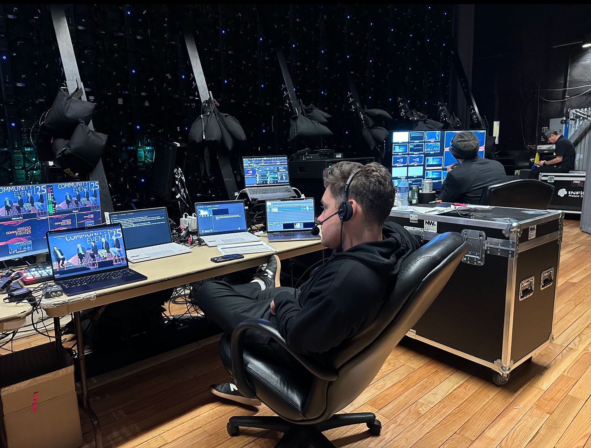 Person at a control desk with multiple monitors in a dark studio or event control room