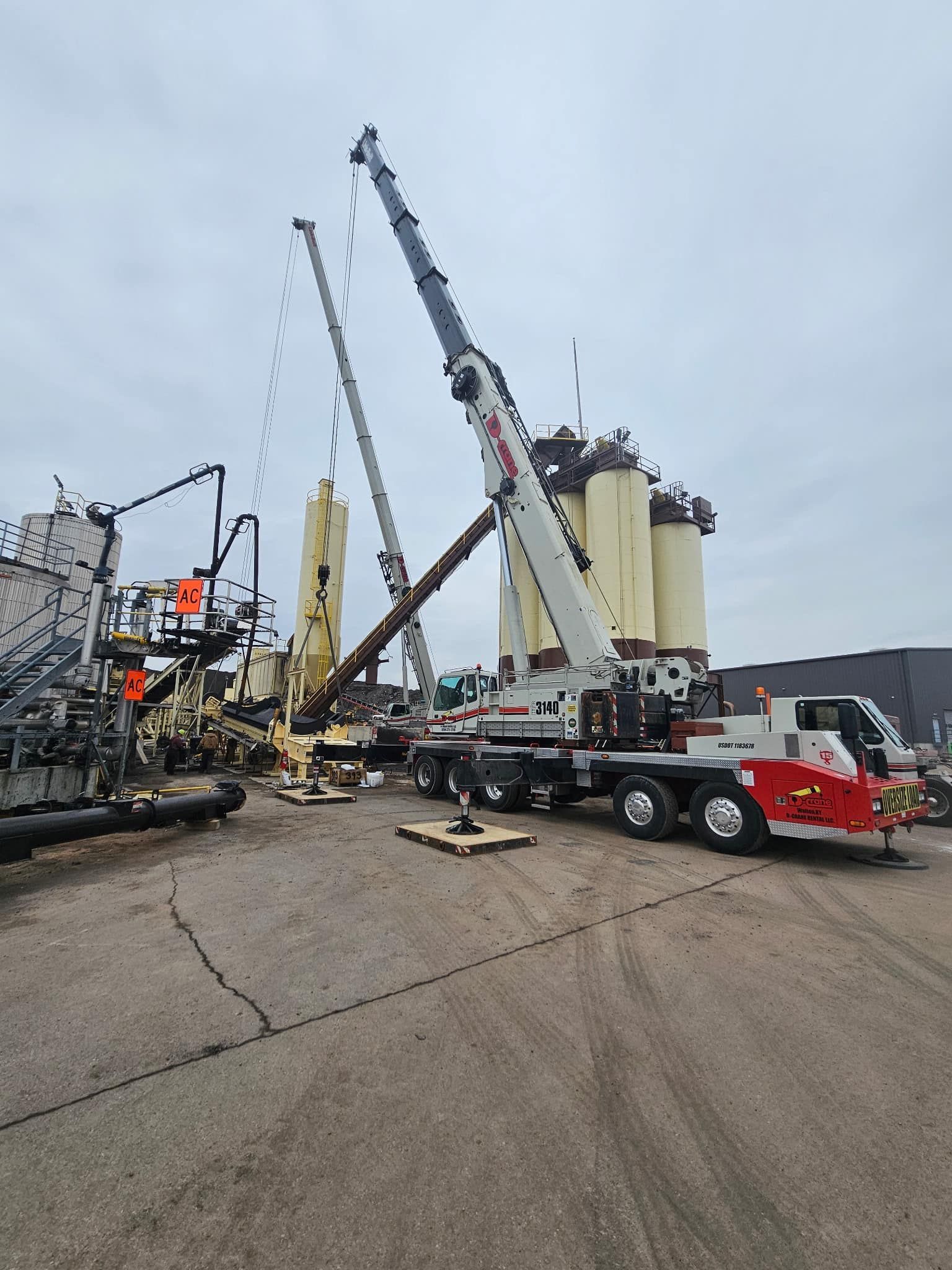 Fire trucks and cranes at a utility repair site on a wet city street