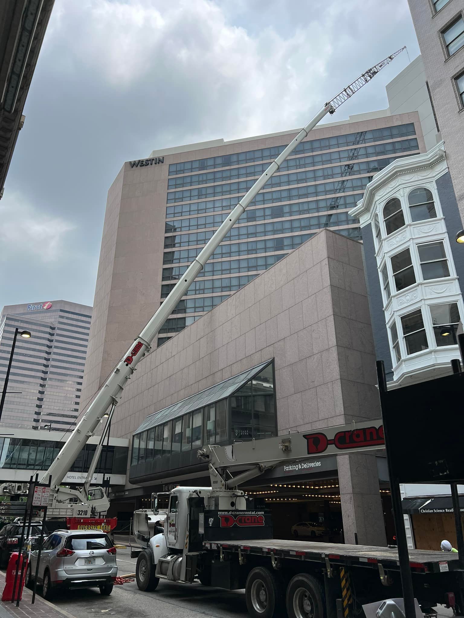 Fire truck with extended ladder on a city street beside a tall building under cloudy skies