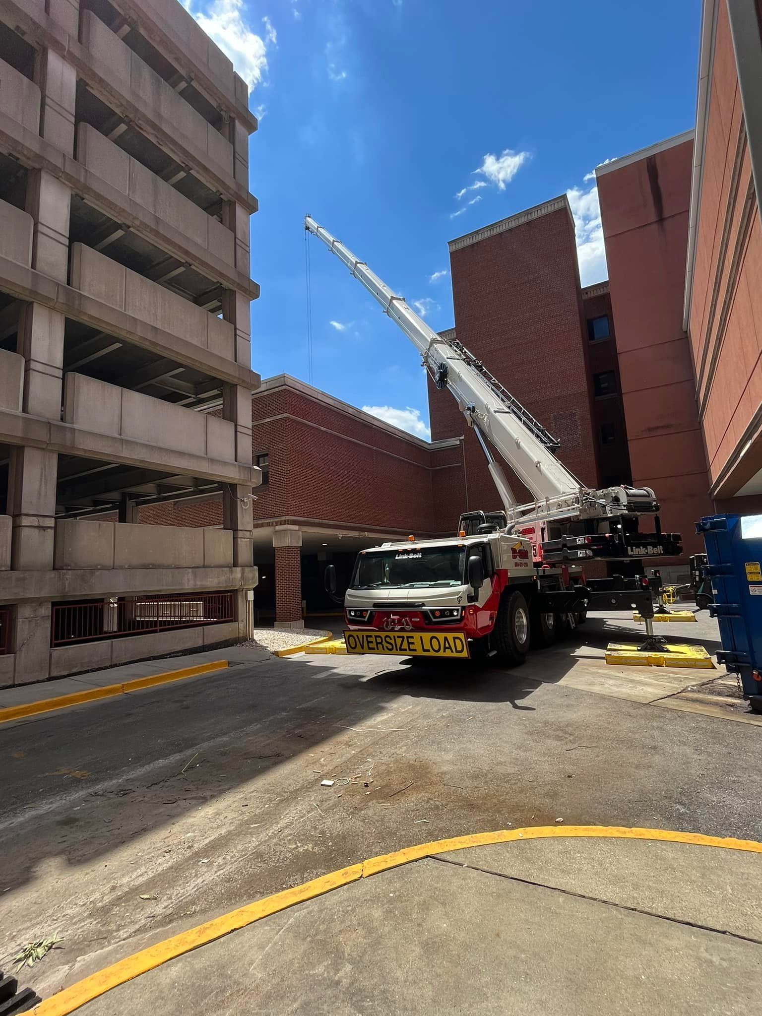 Crane truck in a narrow courtyard between brick buildings under a blue sky