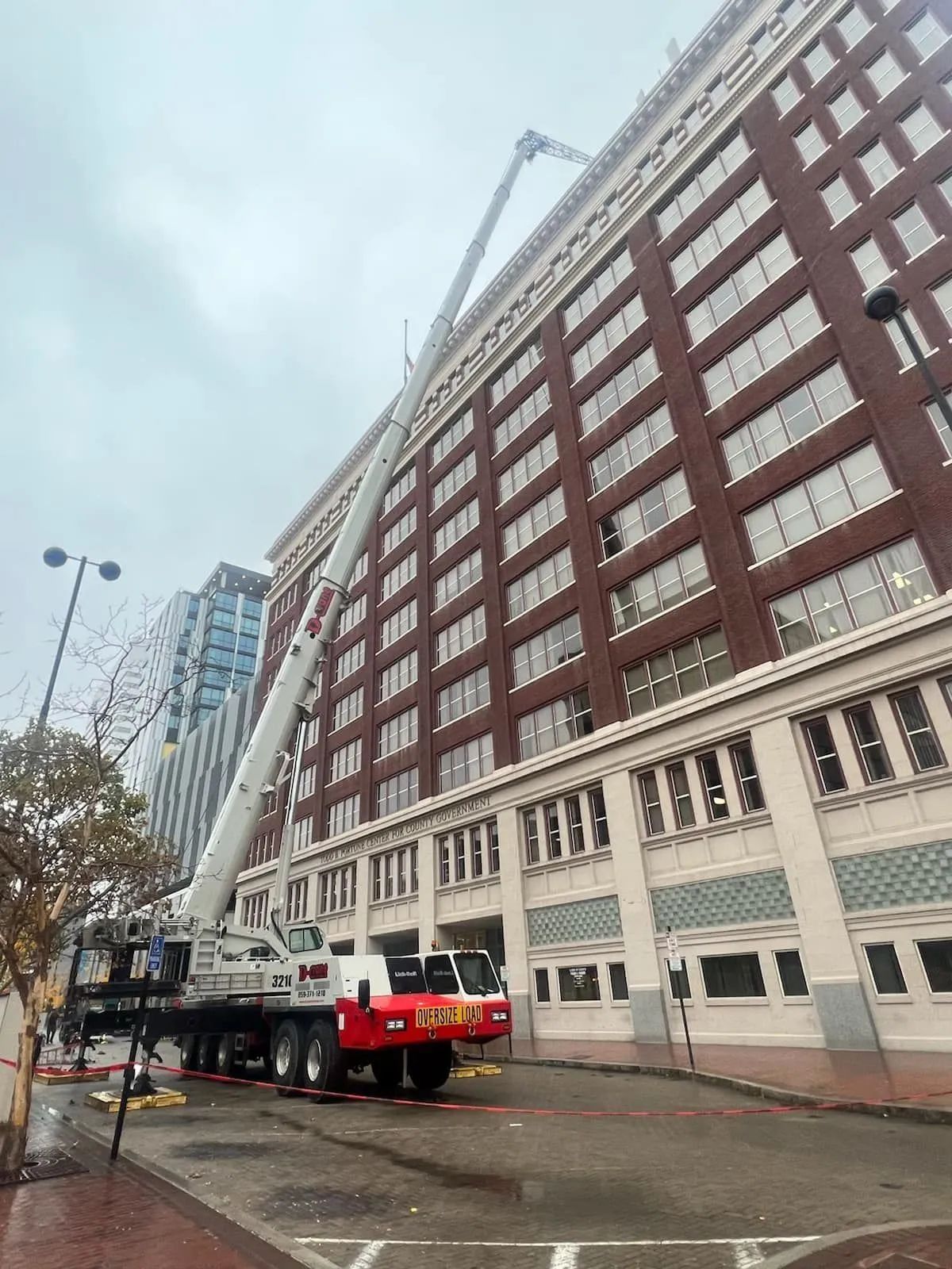 Fire truck extended ladder beside a tall brick building on a rainy city street