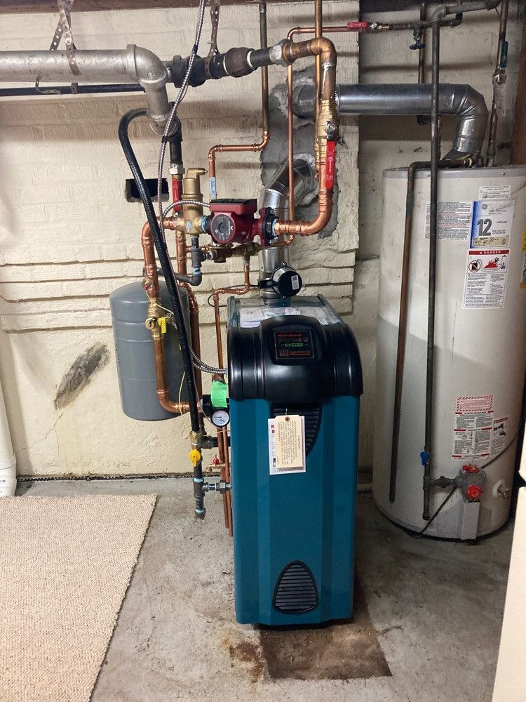 A blue water heater is sitting next to a white water heater in a basement
