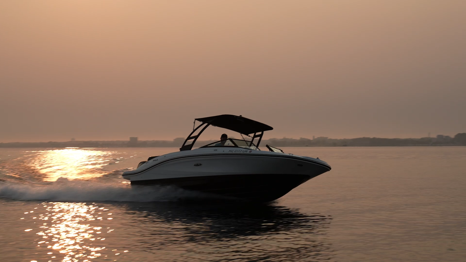 A boat is floating on top of a body of water at sunset.