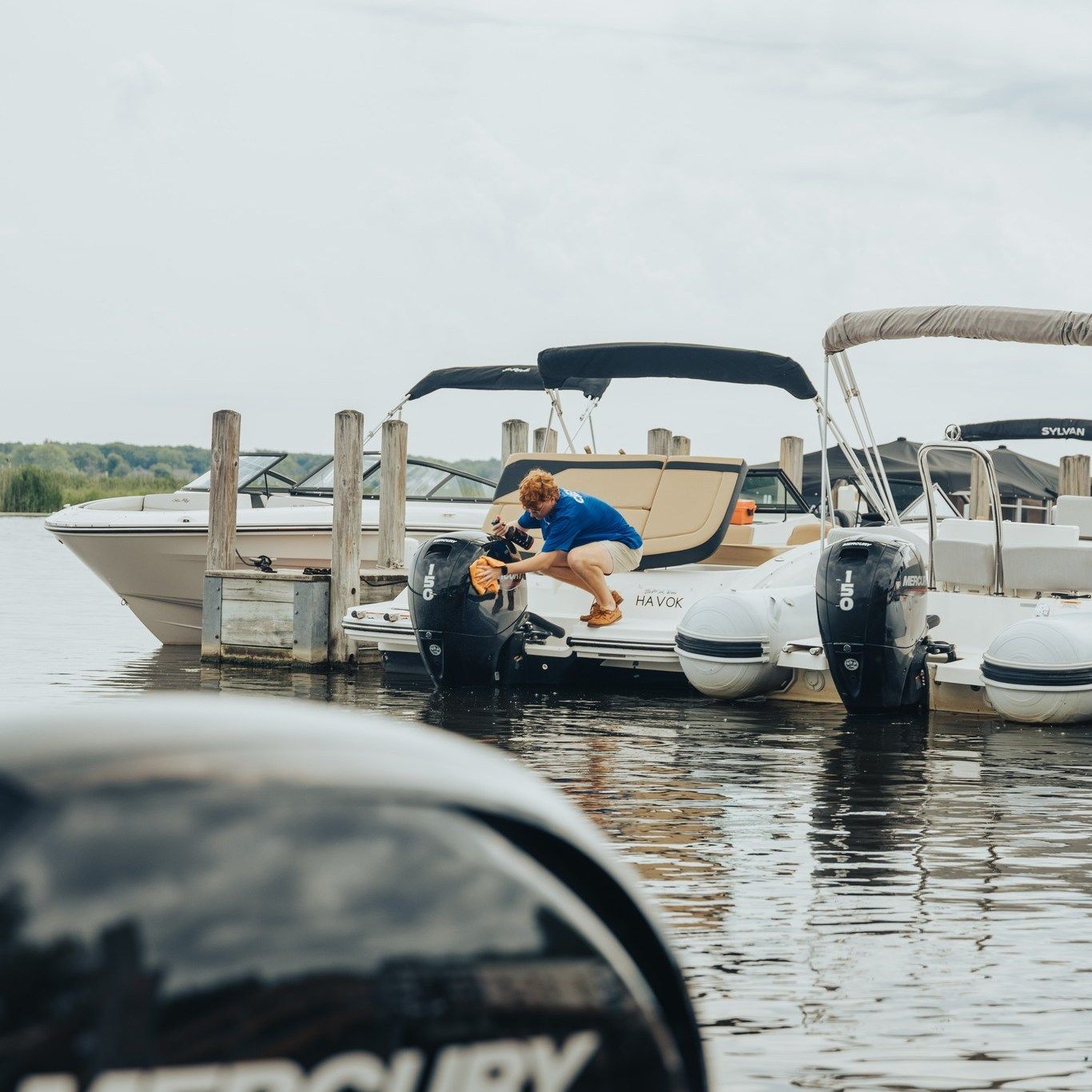 A man is cleaning the tires of a mercury boat