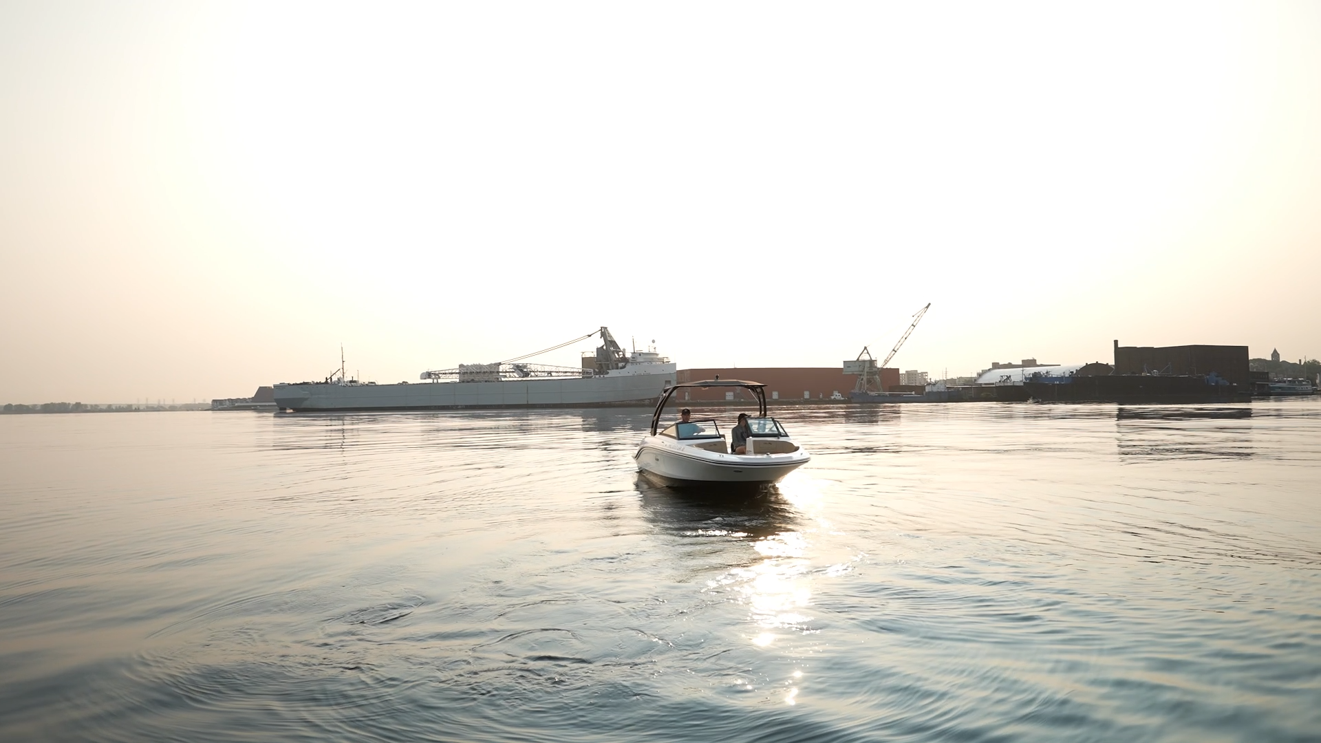 A boat is floating on top of a body of water with a large ship in the background.