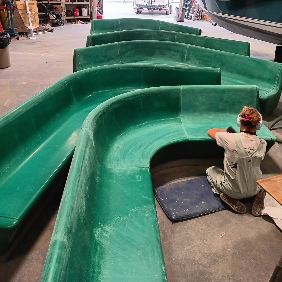 Green curved benches being worked on by a person wearing hearing protection in a workshop.