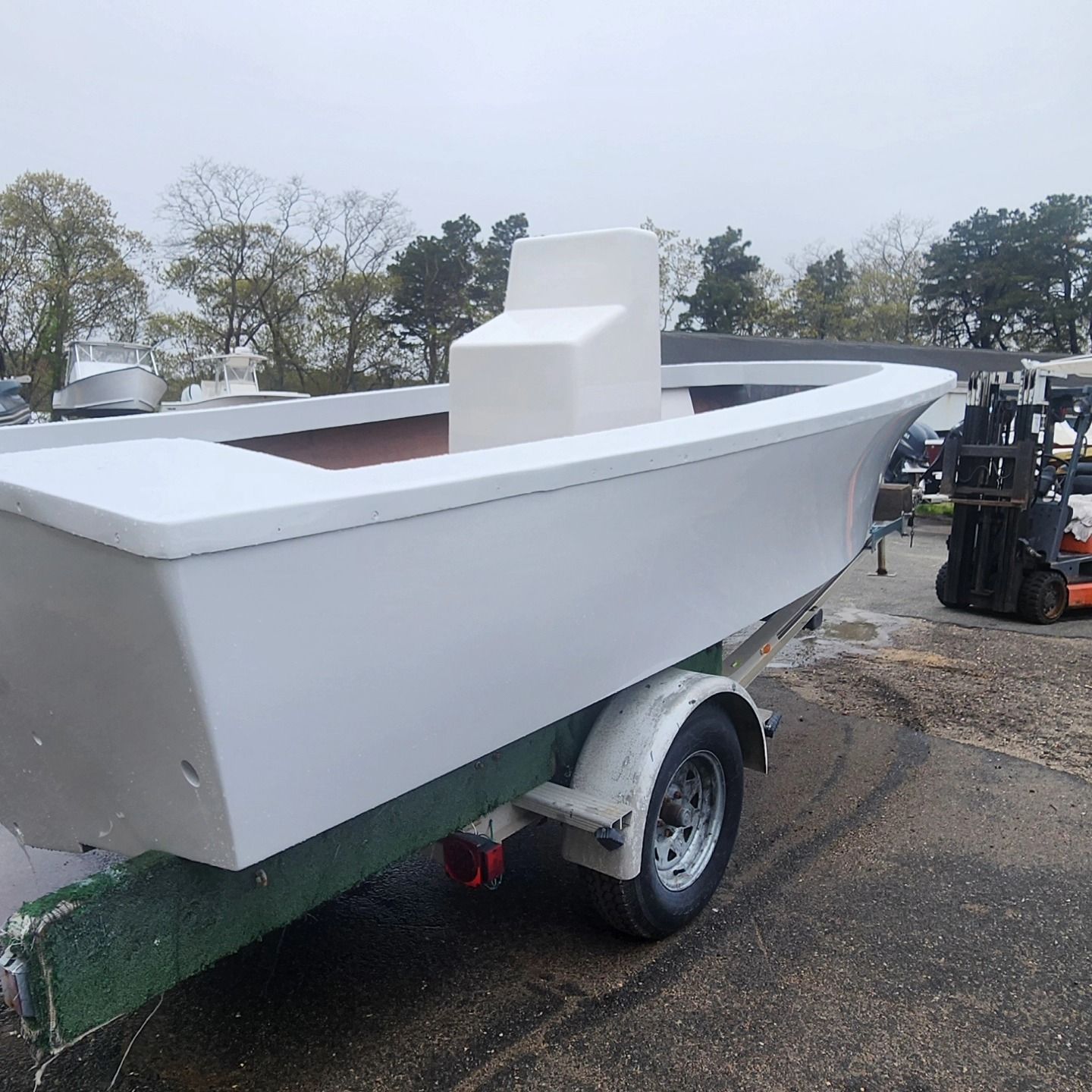 White boat on a trailer, outside, on an overcast day.