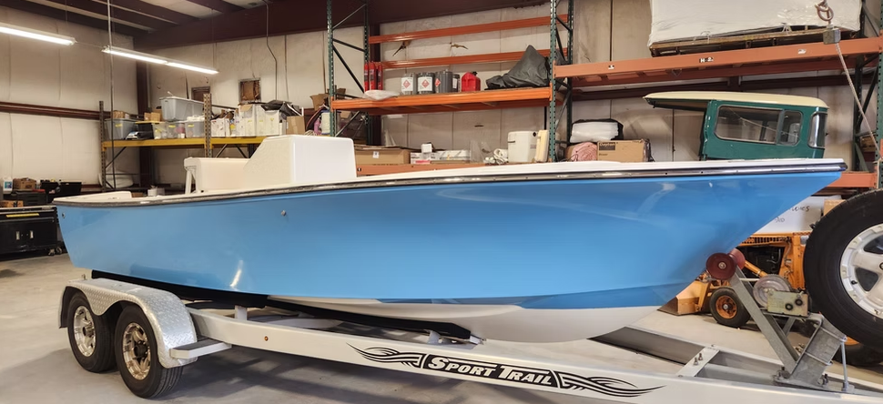 Blue boat on a trailer in a warehouse setting.