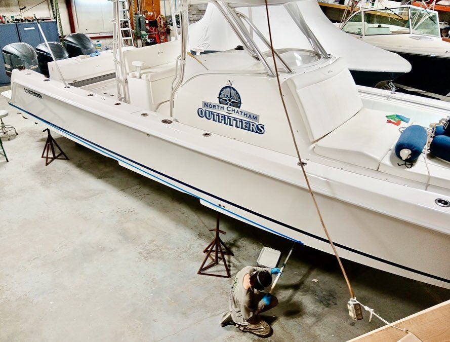 A boat inside a workshop is being worked on by a person.