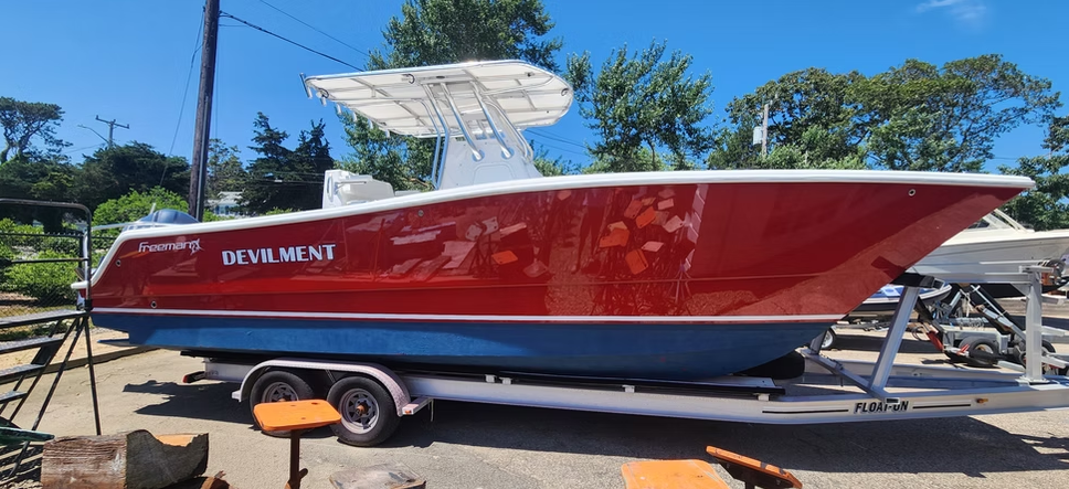 A red and blue boat on a trailer, with 