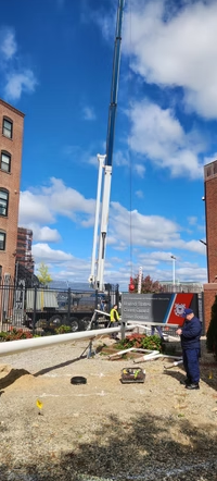 A tall construction crane over a construction site with buildings in the background and two workers.