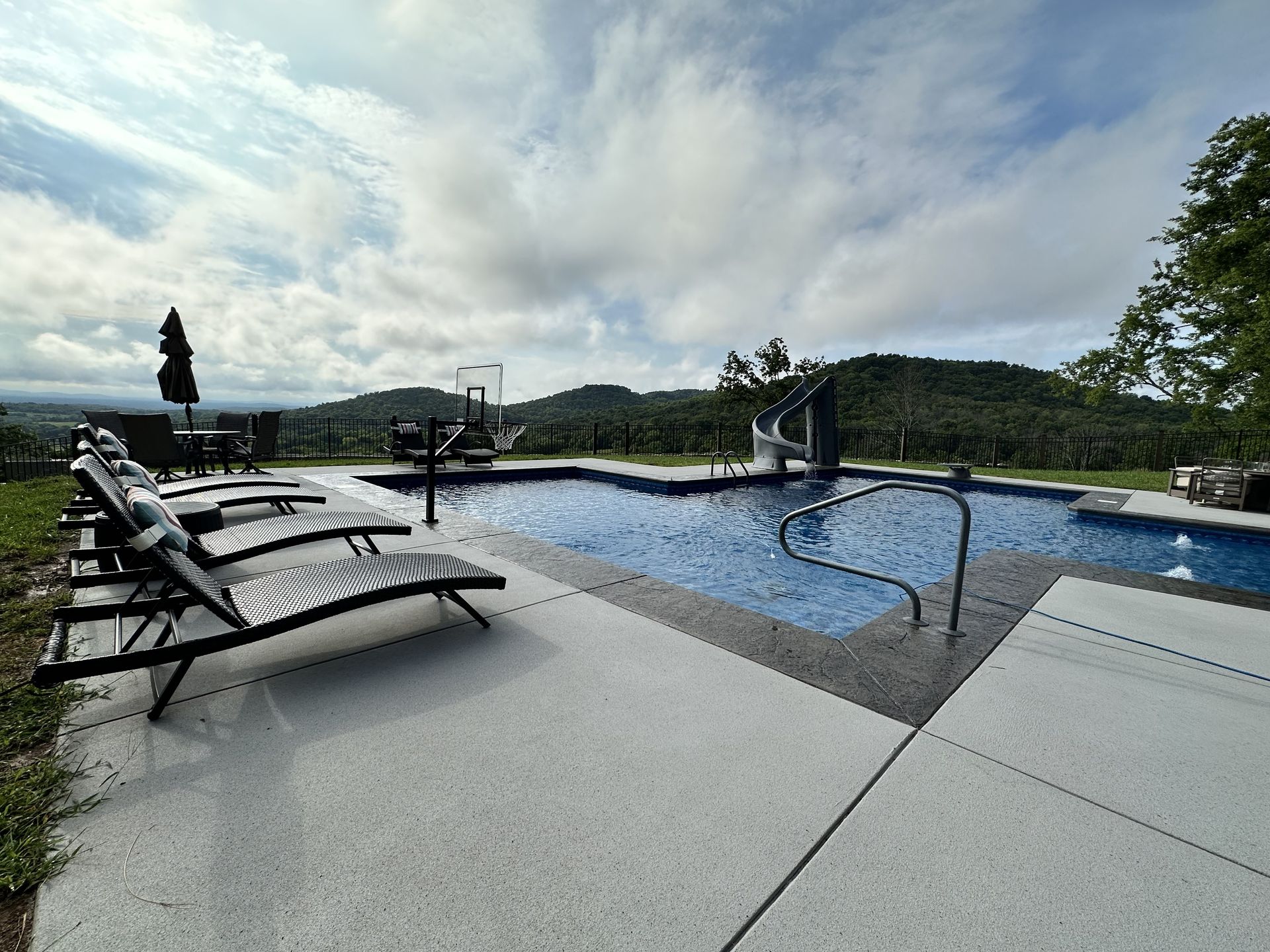 Infinity pool with lounge chairs overlooking a cloudy mountain landscape