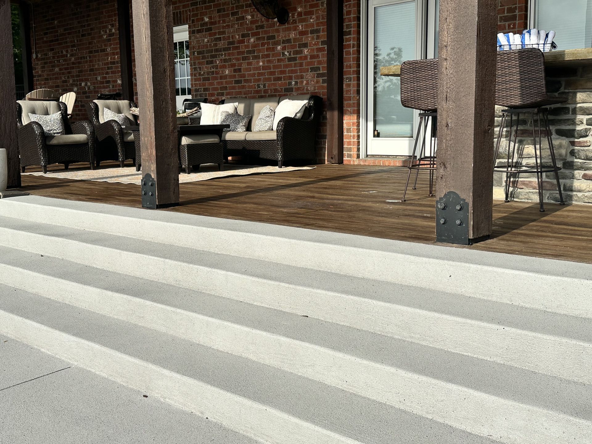 Porch with outdoor seating and striped awning casting shadows on the deck and steps
