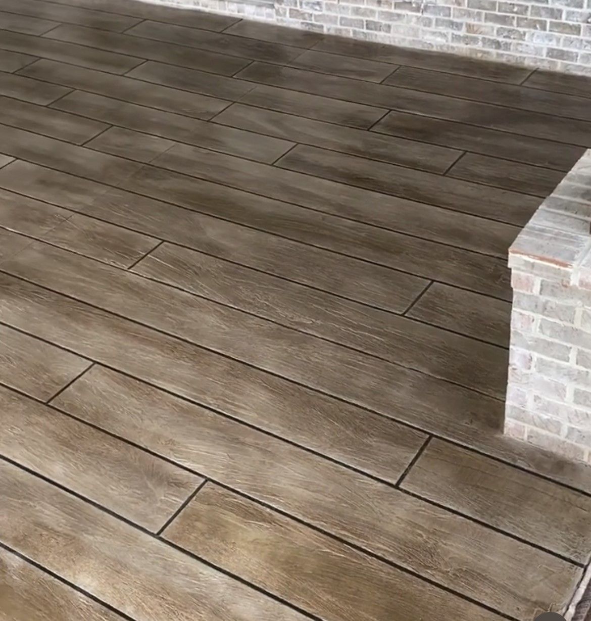 Wooden porch floor with brick walls and a low brick column.
