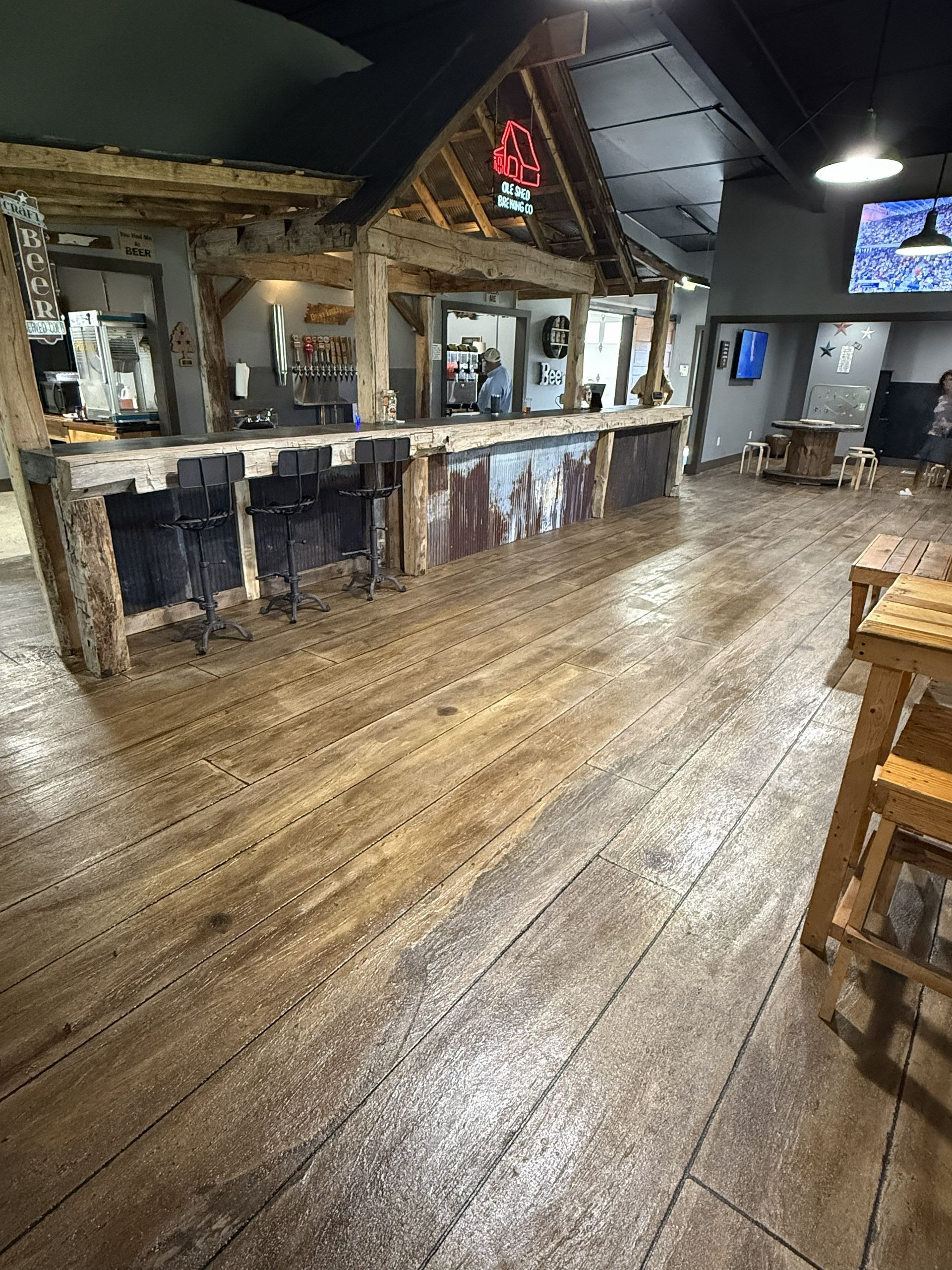 Rustic wooden bar interior with high tables, stools, and warm pendant lighting