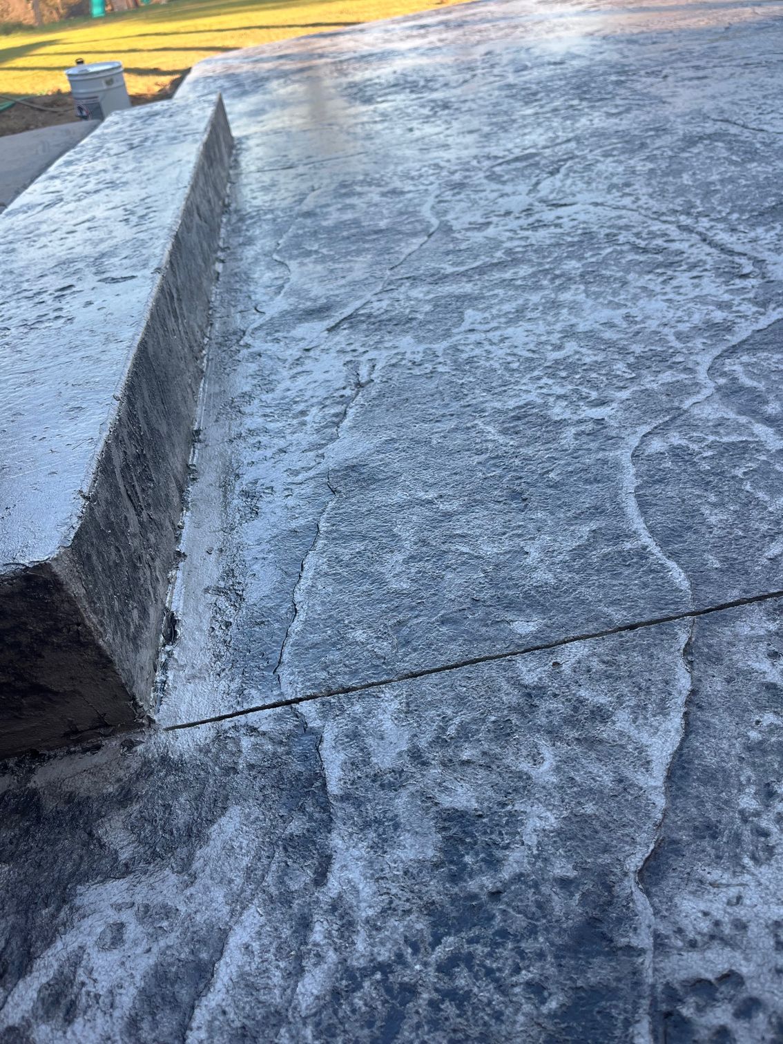 Weathered concrete pavement with a low curb and textured surface in sunlight