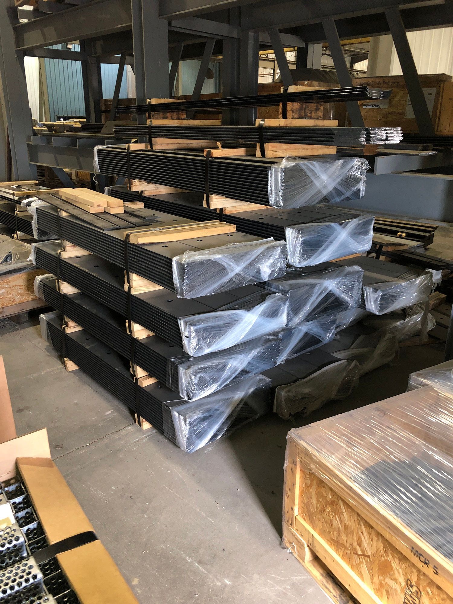 A warehouse filled with lots of metal pieces wrapped in plastic.