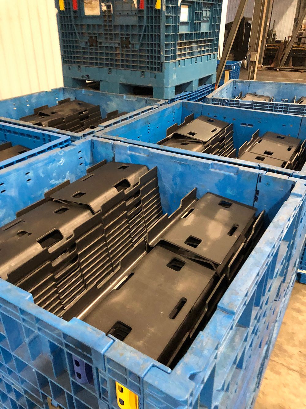 A bunch of blue plastic crates filled with metal parts.