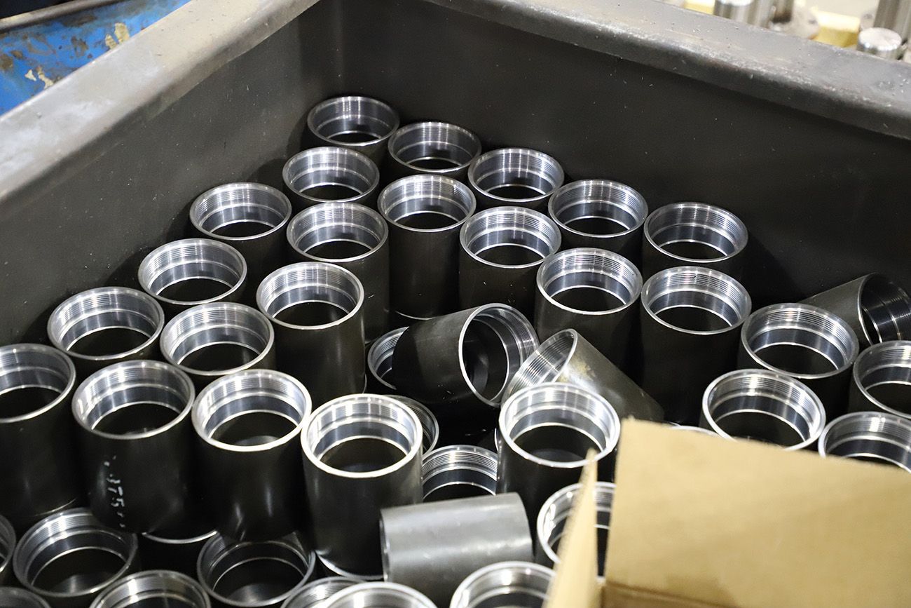 A bin filled with lots of metal pipes and a cardboard box.