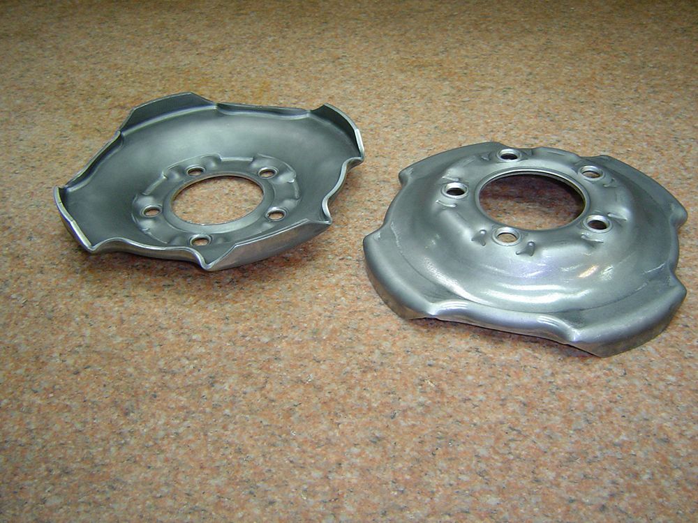 Two metal plates with holes in them are sitting on a carpet