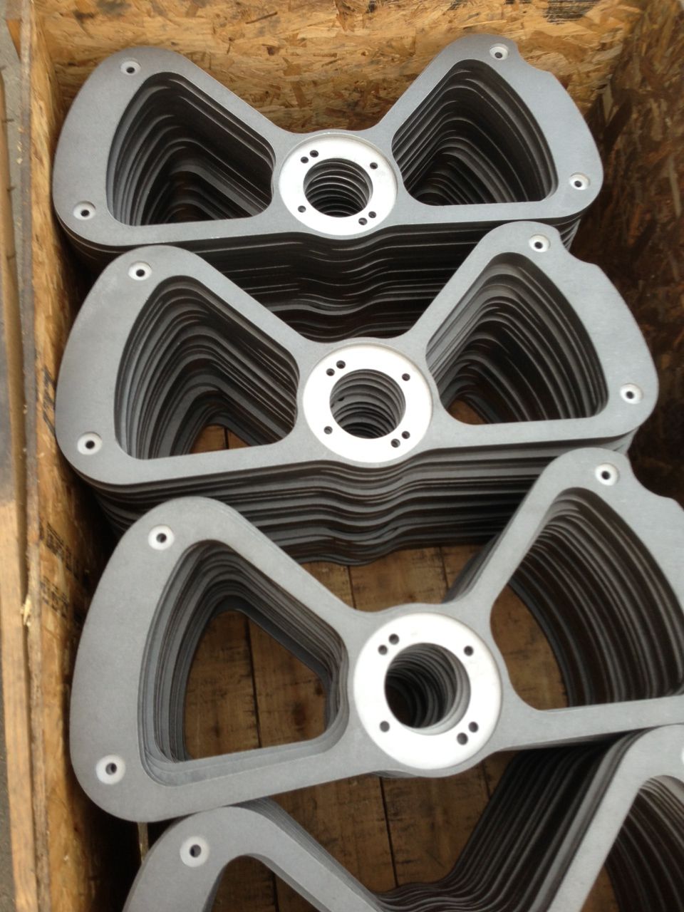 A wooden box filled with a bunch of metal pieces