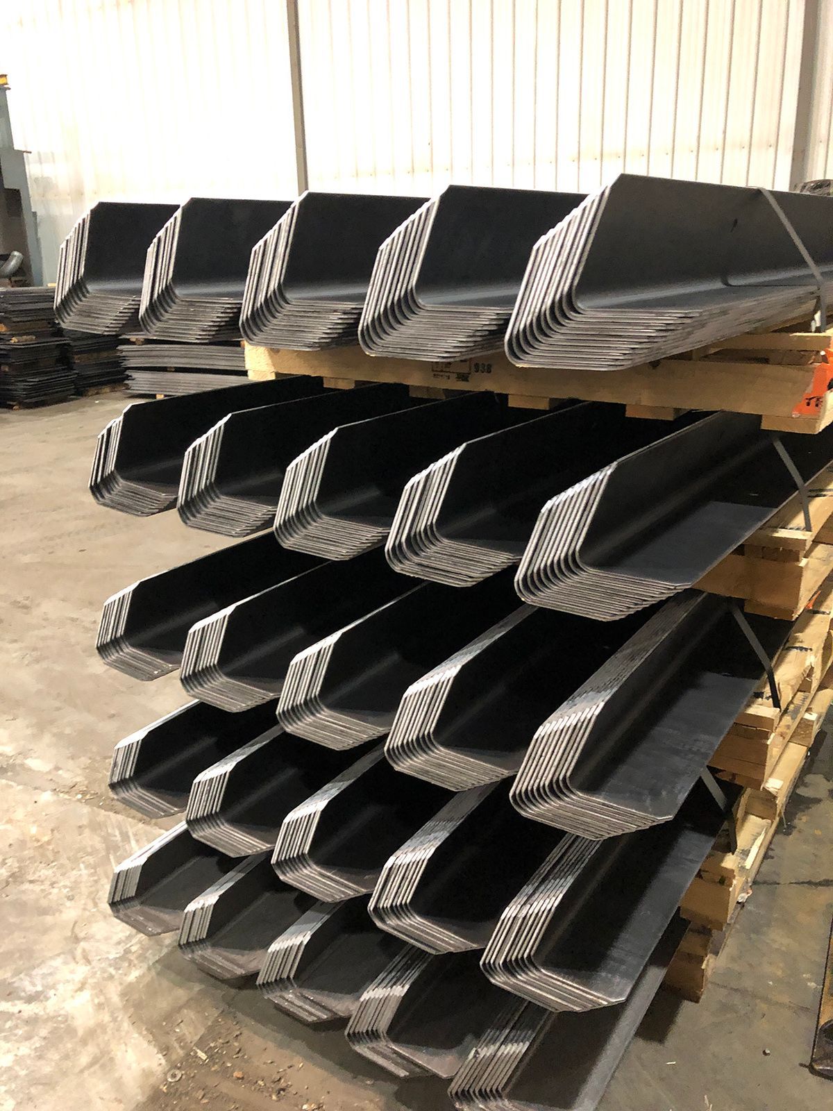 A stack of metal buckets sitting on top of wooden pallets in a warehouse.