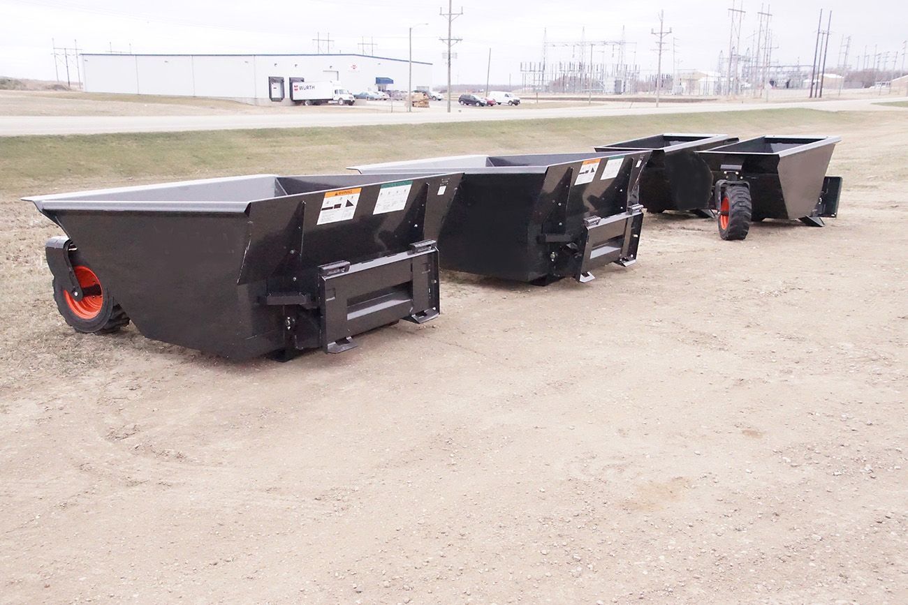 A group of dumpsters are sitting on top of a dirt field.