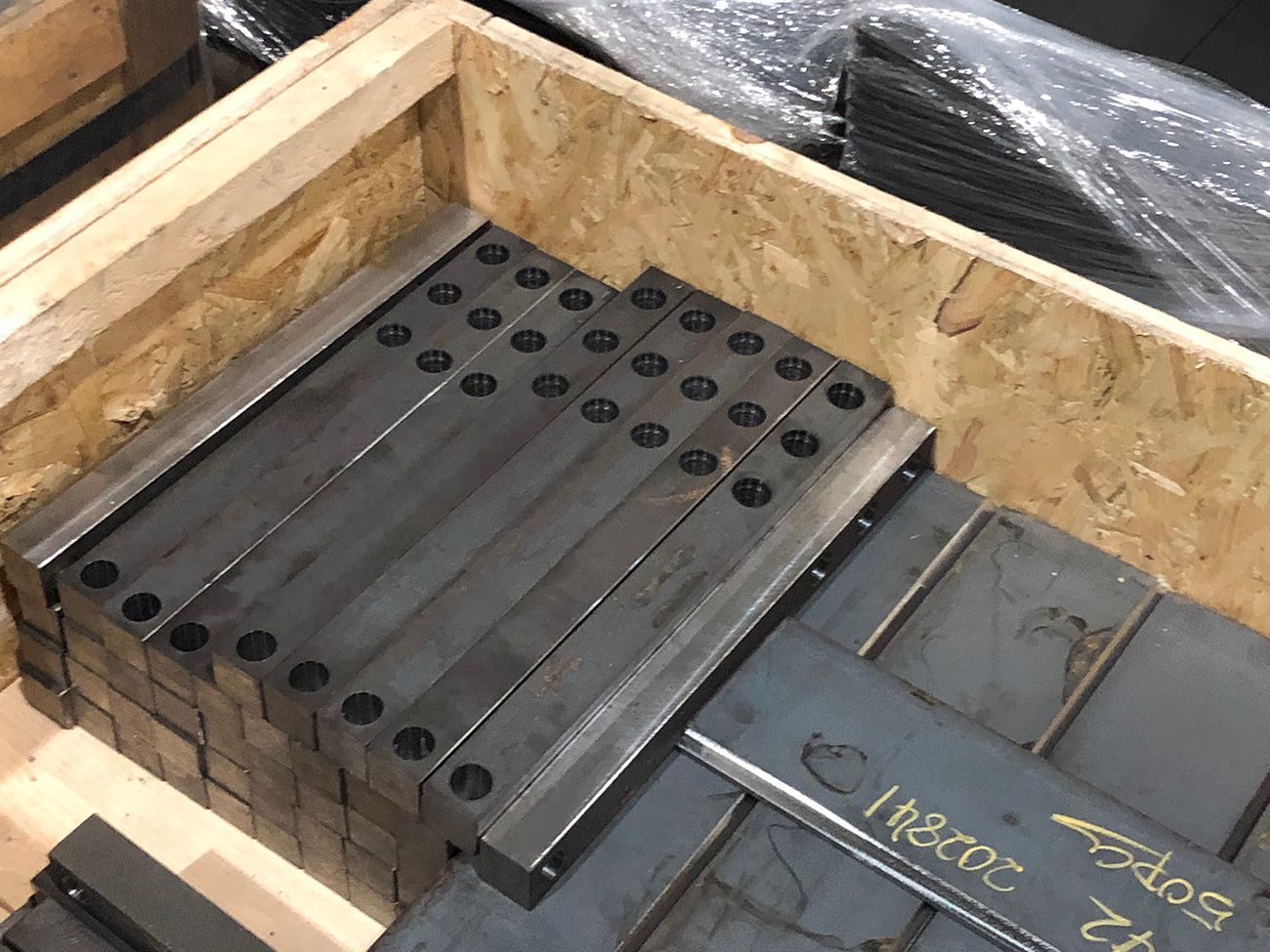 A wooden box filled with a bunch of metal pieces.