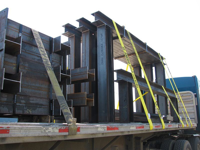 A truck is carrying a large stack of steel beams