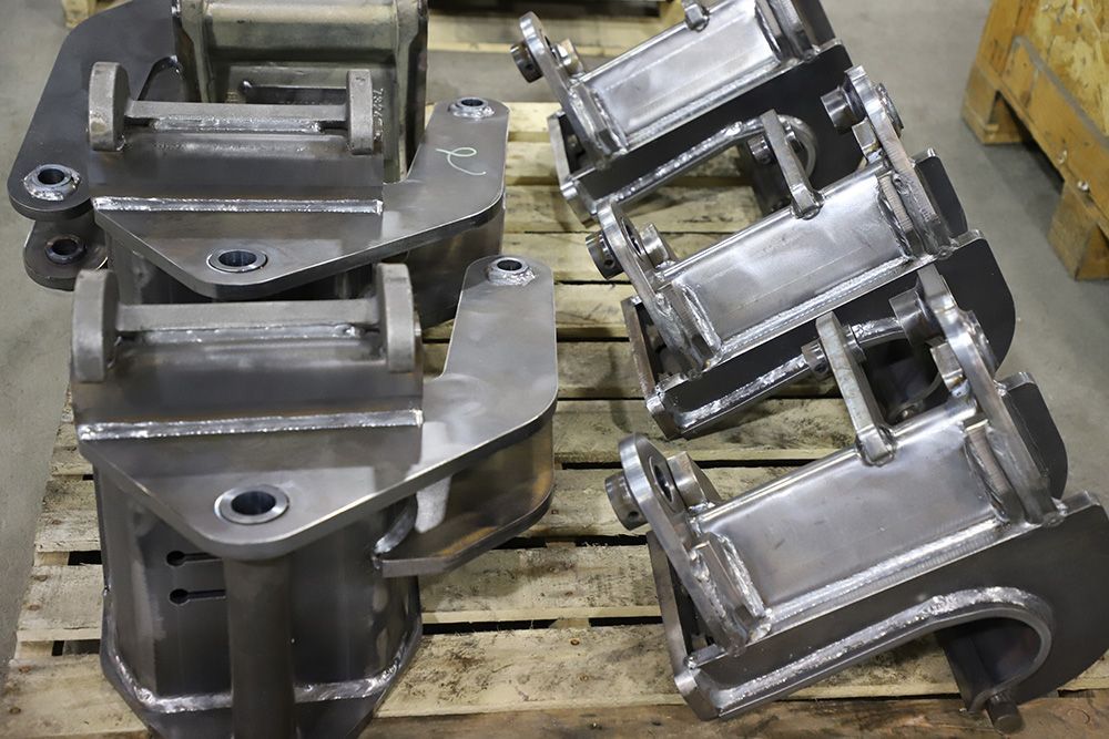 A bunch of metal parts are stacked on top of each other on a wooden pallet.