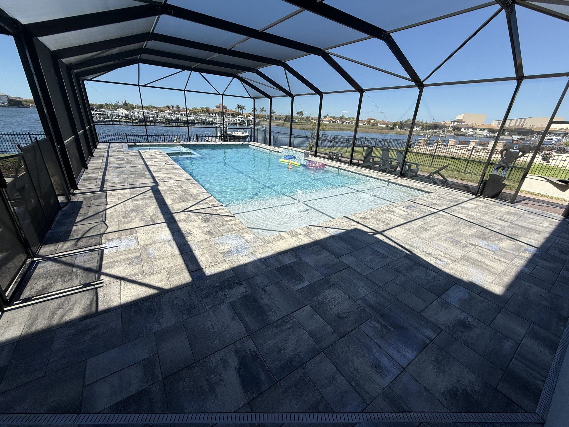 Screened pool deck with a small blue pool overlooking a waterfront and city skyline