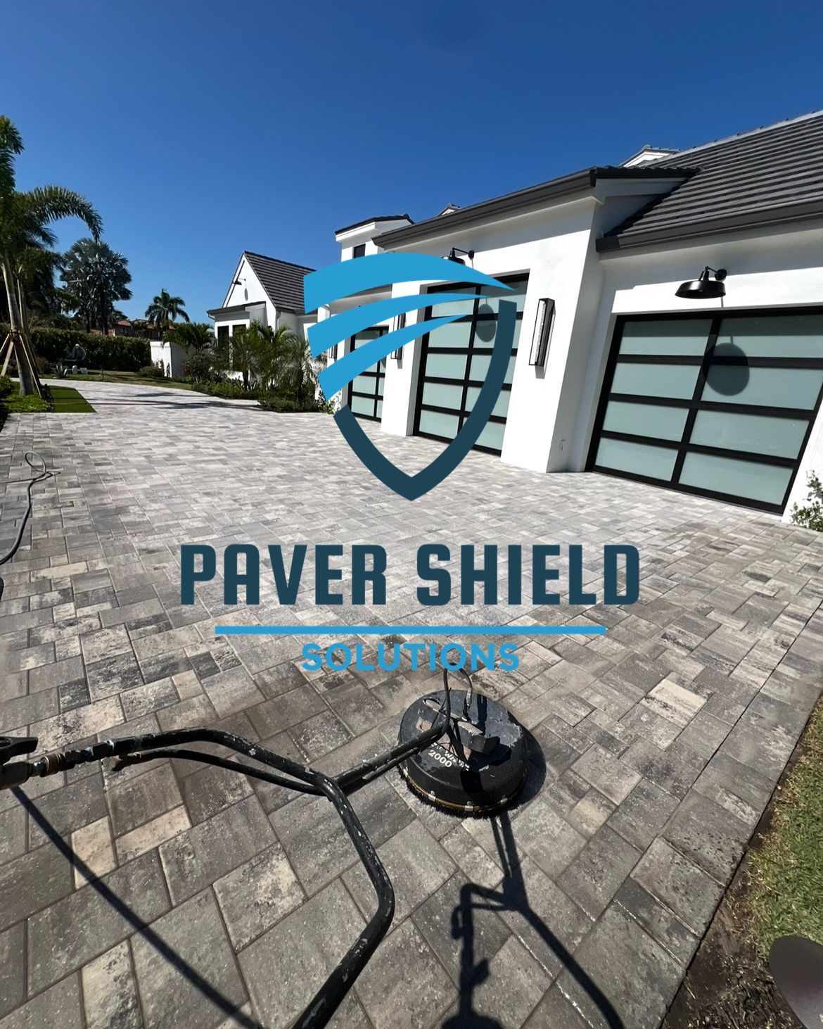 Logo on a patio paver surface with a house and blue sky in the background.